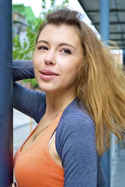 Mooie roodharige meisje in een oranje shirt met zich meebrengt in de buurt van een lantaarnpaal — Stockfoto