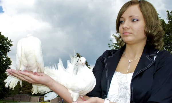 Linda chica rusa sostiene dos palomas blancas en sus manos — Foto de Stock