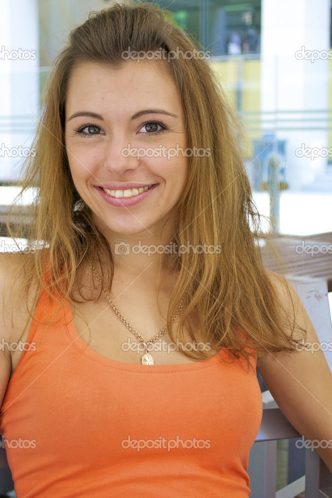 Beautiful red-haired young girl in an orange shirt smiles