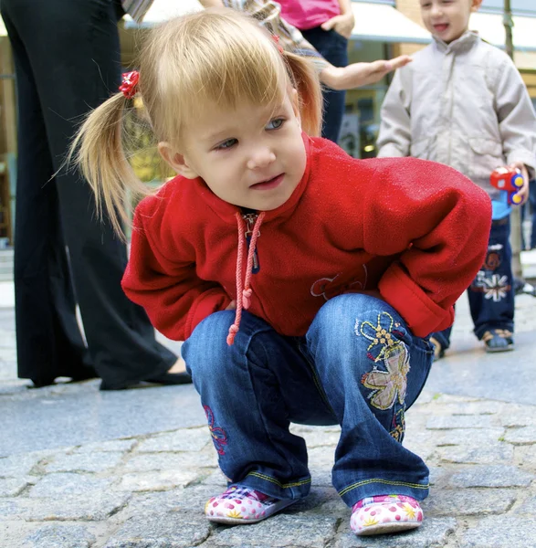 Cute dziewczynka siedzi na ziemi — Zdjęcie stockowe