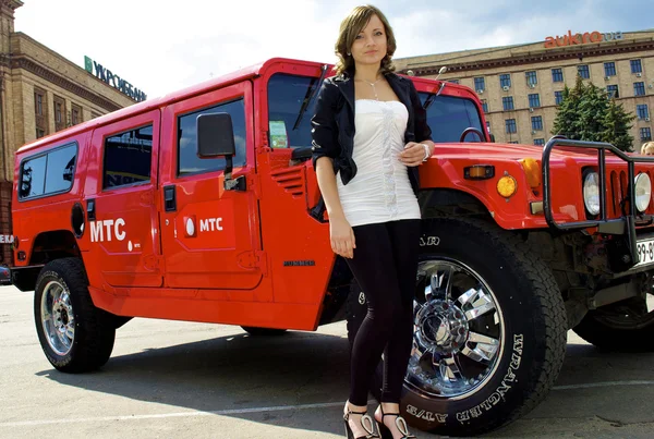 Cute girl poses near red hummer — Stock Photo, Image