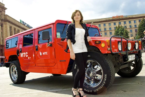 Aranyos lány jelent közelében piros hummer — Stock Fotó