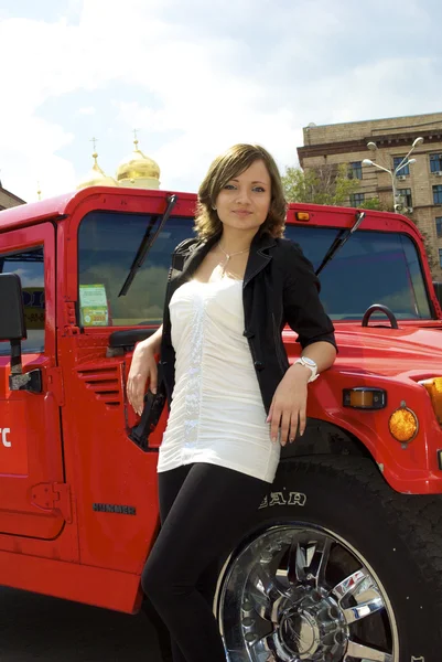 Cute girl poses near red hummer — Stock Photo, Image