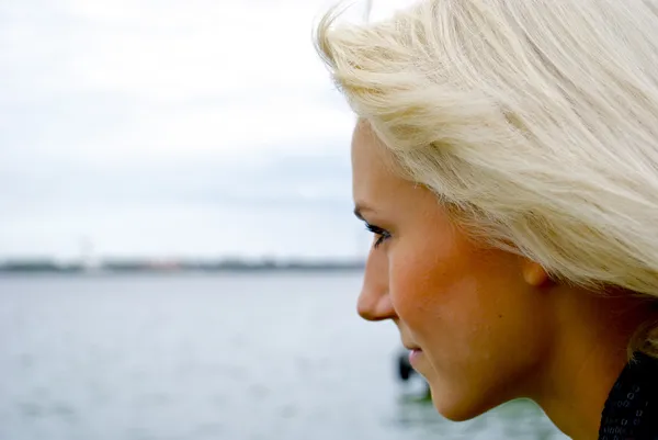 Prachtige blond Kaukasische model meisje kijkt op de rivier — Stockfoto