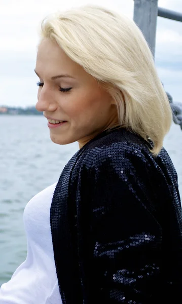 Ładny blond modelu kaukaski dziewczyna w czarny płaszcz i jeansy spodenki stawia na t — Zdjęcie stockowe