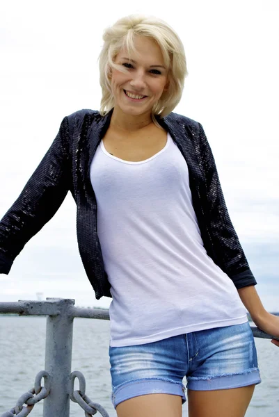 Vacker blond kaukasiska modell flicka i svart kavaj och jeans på piren — Stockfoto