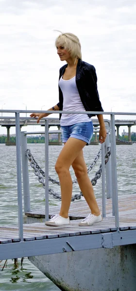 Linda menina modelo loira caucasiana em casaco preto e jeans posa no — Fotografia de Stock