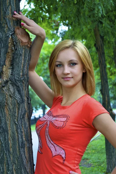 Güzel cinsel genç sarışın kızı ağaca yakın bir turuncu gömlek