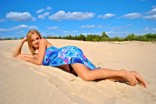 Menina semi-nua coberta com um tecido posa na areia — Fotografia de Stock