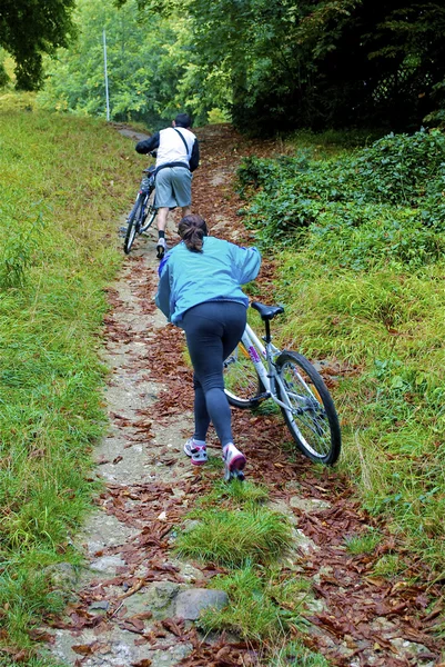 Homem e sua esposa com as bicicletas vão uphiil — Fotografia de Stock