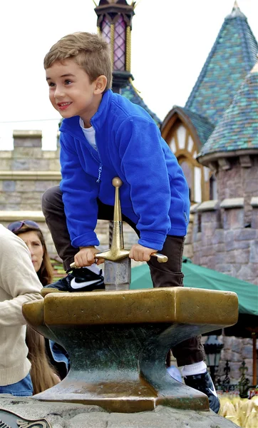 Boy tries to take the sward out of the stone — Stock Photo, Image