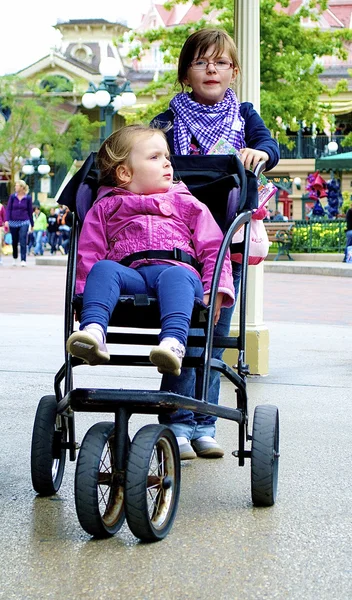 Flickan bär sin syster i barnvagn — Stockfoto