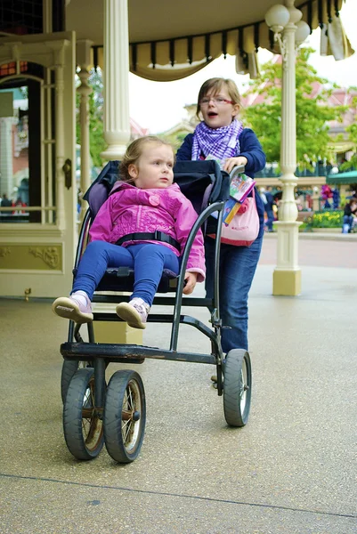 Menina carrega sua irmã em um carrinho — Fotografia de Stock