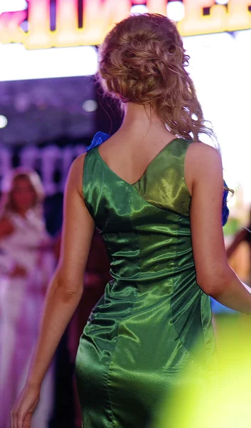 Amazing blonde contestant walks over the runway in a green dress — Stock Photo, Image