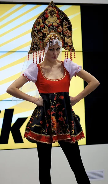 Beautiful girl poses in Russian costume supporting NIKON — Stock Photo, Image