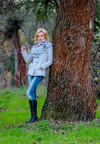 Menina bonita posa na floresta vestindo casaco e jeans — Fotografia de Stock