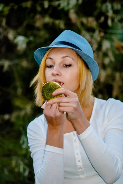 Blon fille dans un chapeau fait un maquillage — Photo