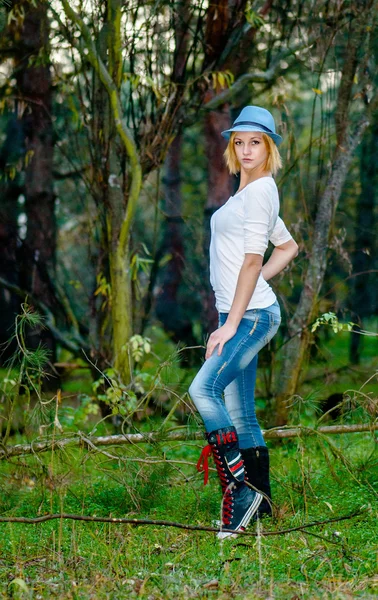 Modello caucasico posa in un cappello e jeans nella foresta — Foto Stock