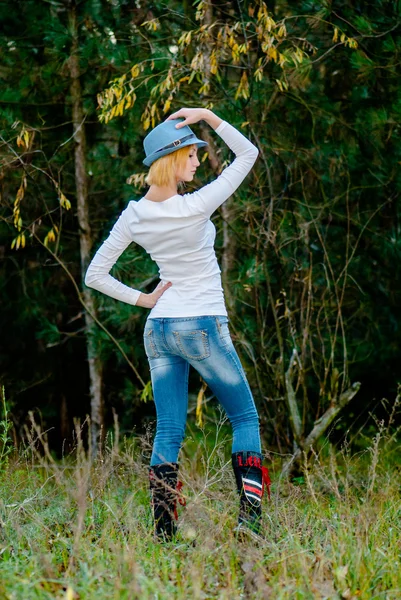 Modelo caucásico posa en un sombrero y jeans en el bosque —  Fotos de Stock