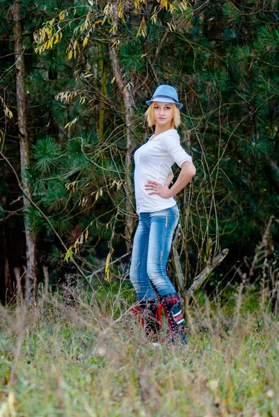 Mooi meisje houdingen in het woud in herfst dragen mode hoed en jeans — Stockfoto