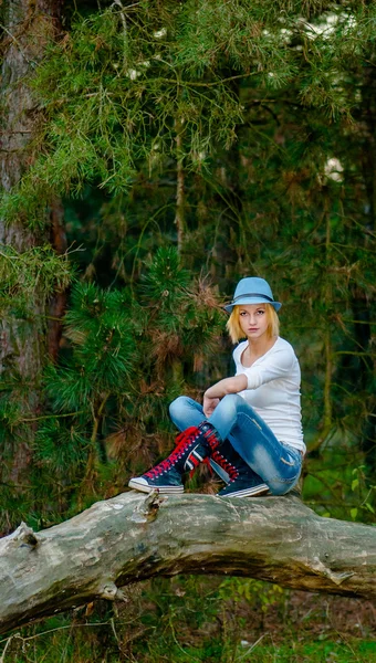 Bella ragazza russa si siede sull'albero e posa in cappello e vestiti di moda — Foto Stock