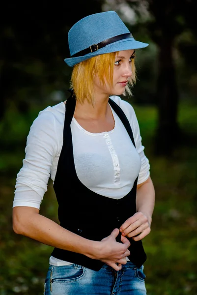 Θέτει την όμορφη ξανθιά κοπέλα στο δάσος με καπέλο και της μόδας ρούχα — Φωτογραφία Αρχείου