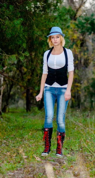 Schöne blonde Mädchen posiert im Wald in Hut und Modekleidung — Stockfoto