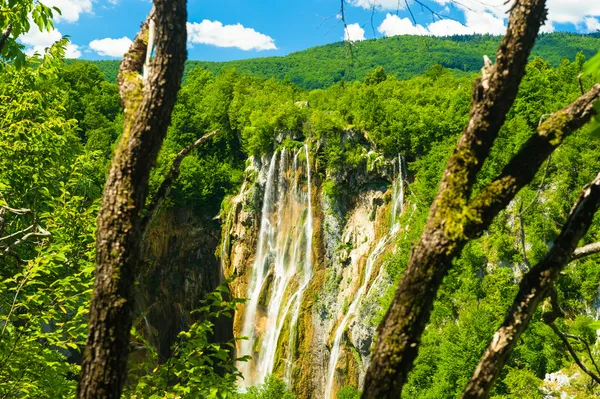 Schöner Felsen mit Wasserfall unter blauem Himmel mit Wolken — Stockfoto