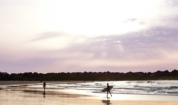 Siluetas de surfistas paseando por la playa — Fotografia de Stock