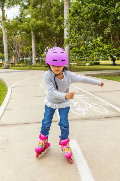 Little girl is skating with her roller skates on the rink