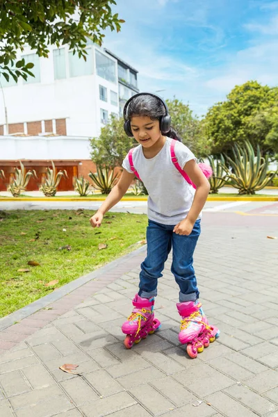 Little girl is skating with her roller skates on the rink