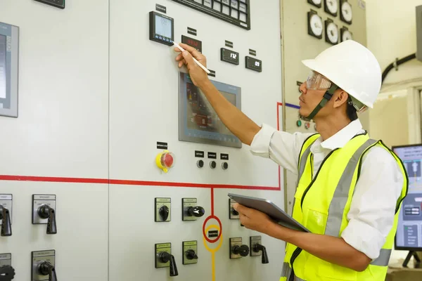 技術者は チェックステータススイッチギア電気エネルギー分配ステーションに取り組んでいます 電気スイッチルームでの電気およびツールのロギング情報 — ストック写真