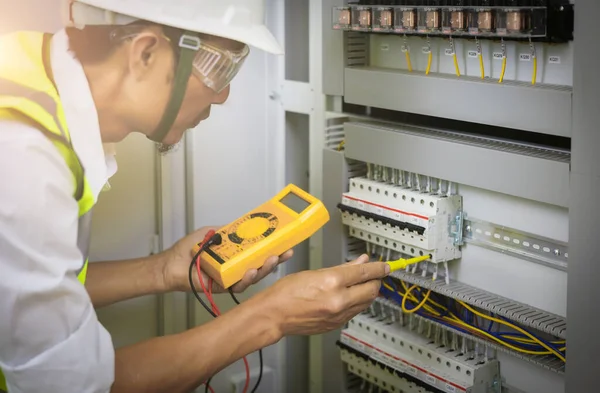 Electrical engineers test the voltage and current of the wires in the electrical cabinet control.the multimeter is in the hands of the electrician details