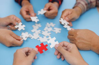 Bir grup iş adamı mavi arka plan, takım çalışması, iş dünyasında yardım ve destek, ortaklık ve bağlantının sembolü olan yapboz parçalarını bir araya getiriyorlar. iş stratejisi.