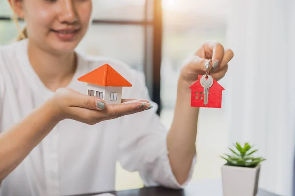 Your new house, real estate agent holding house key to his client after signing contract agreement in office,concept for real estate, renting property