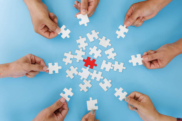 Руки разных людей, собирающих головоломку, команда собирает части вместе в поисках правильного соответствия, помогает в командной работе, чтобы найти общую концепцию решения, вид сверху
