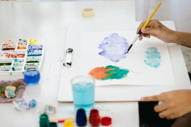 Suluboya ve fırçalarla sanat yaratmak için evdeki bir çizim tahtasına yakın plan boya..