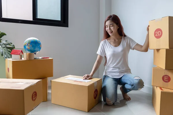 Woman packing to move to a new house. Pack a box on the floor, relocate and move to a new apartment.