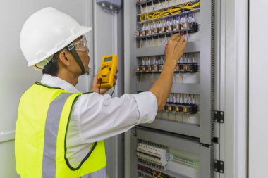 Electrician installing electric cable wires and fuse switch box. Multimeter in hands of electricians detail.
