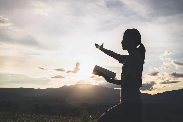 Silhouette of The girl  prayed  in the mountains to think of a loving God, we praise God.