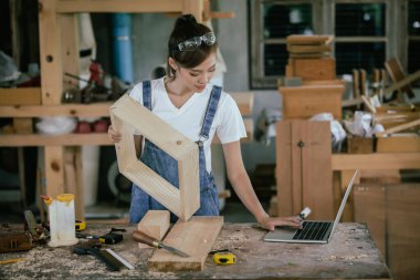 Professional carpenter. A woman works in a carpentry shop using a tablet to design furniture in a wood shop.