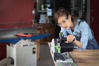 woman works in a carpentry shop. Carpenter working on woodworking machines in carpentry shop. 