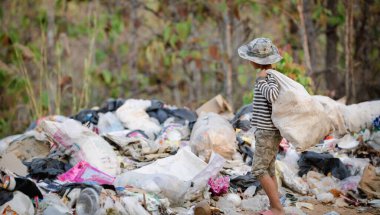 A poor Indian rag picker boy carrying a huge load of garbage collected during the day. Child labor in Indian cities due to poverty stricken children.