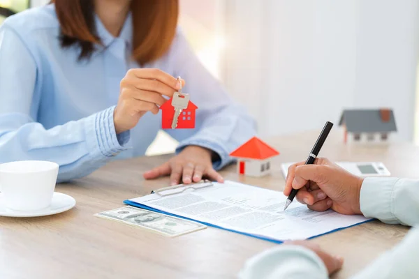 Home sales and home insurance concept. Real estate agent talked about the terms of the home purchase agreement and asked the customer to sign the documents to make the contract legally.