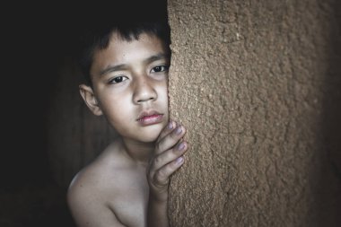 The poor boy snuck by the door, his eyes sad and despaired. Human trafficking concepts and fear of children, violence, poverty, human rights