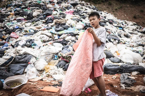 A poor boy collecting garbage waste from a landfill site in the outskirts. Poverty and child labor concept, human trafficking.