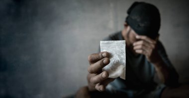 Adamın elinde plastik paket ya da torba kokain ya da başka bir uyuşturucu, uyuşturucu kullanımı ve tehlike bağımlılığı konsepti var. Uyuşturucu kullanmayı bırak..