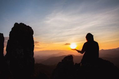 silhouette of man rise hand up praying  on top of mountain and sunset sky abstract background. Freedom and travel adventure concept. 
