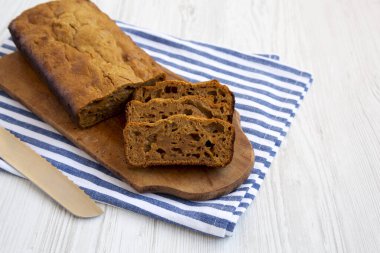 Beyaz ahşap bir yüzey üzerinde ahşap bir tahtanın üzerinde ev yapımı balkabağı ekmeği..