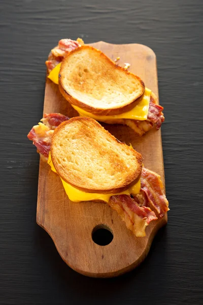 自家製ベーコングリルチーズ黒を背景に素朴な木の板にサンドイッチ サイドビュー — ストック写真